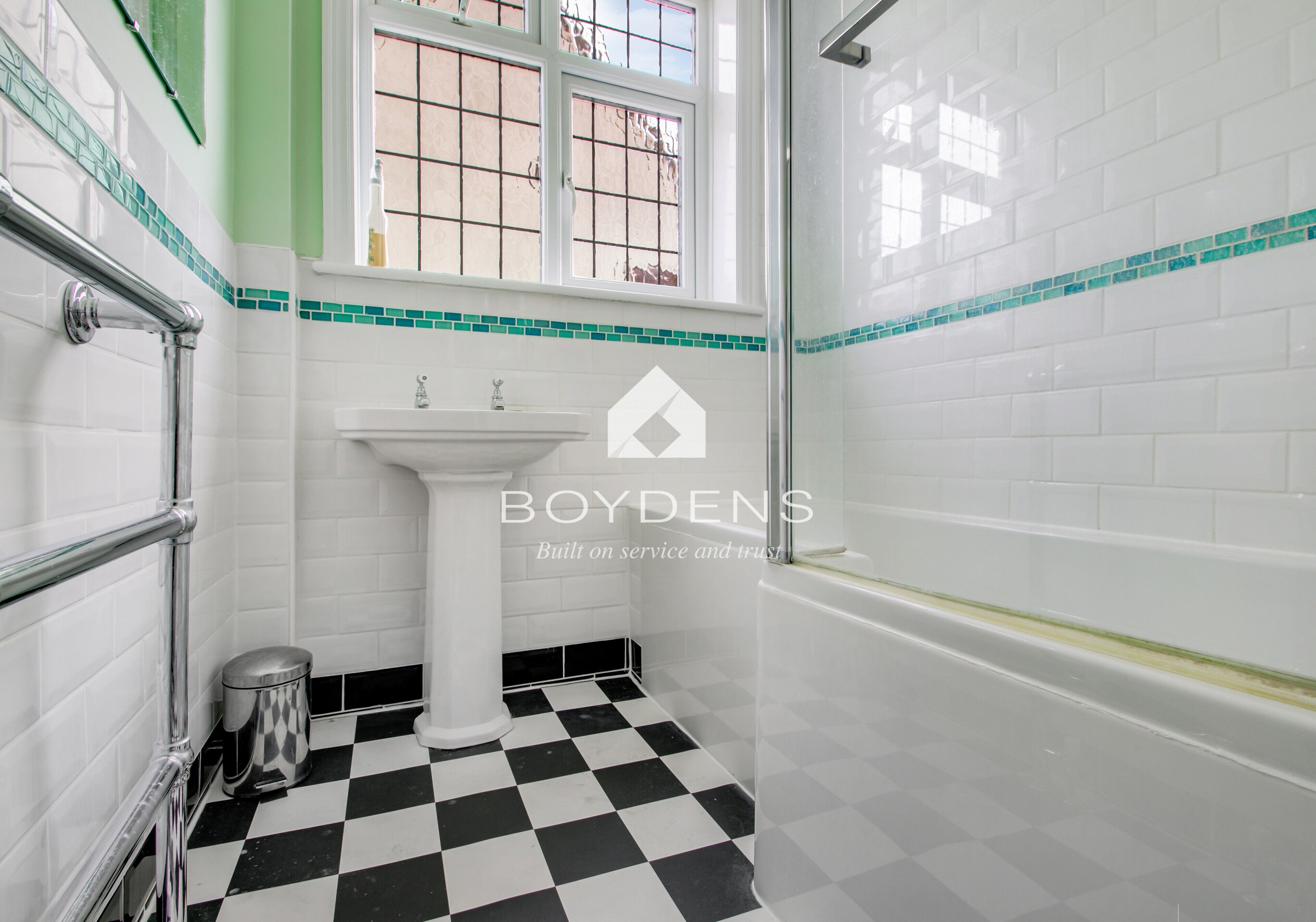A bathroom with a white sink, a black and white checkered floor, and a window with a view.
