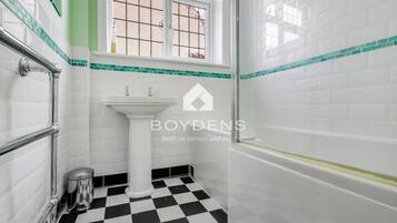 A bathroom with a white sink, a black and white checkered floor, and a window with a view.