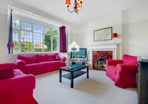 A living room with a red sofa, a coffee table, and a fireplace.