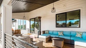 Un espace extérieur aménagé avec des meubles en osier, un canapé bleu et une grande fenêtre donnant sur le paysage.
