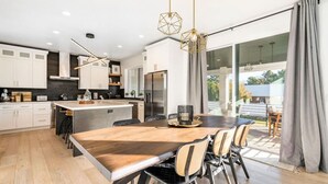 Une cuisine moderne avec des meubles blancs, une table à manger en bois et un grand îlot central.
