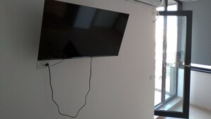 Un téléviseur à écran plat fixé au mur, avec un câble qui y est raccordé.