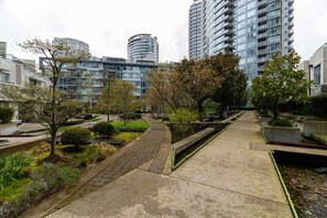 A modern urban residential area with high-rise buildings, a paved walkway, and landscaped greenery.