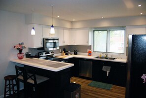 Una cocina moderna con una isla central, electrodomésticos de acero inoxidable y un ventanal que proporciona luz natural.