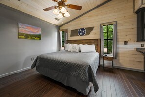 A bedroom with a bed, wooden ceiling, and a window with curtains.
