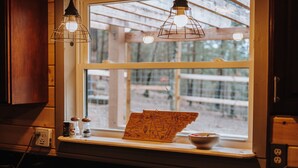 A kitchen with wooden cabinets, a window with a view of trees, and a map on the windowsill. - Pet Friendly! Hot Tub | Pool Table | Fire Pit (Pigeon Forge)