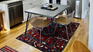 Una cocina moderna con tragaluz, electrodomésticos de acero inoxidable y una zona de comedor con alfombra estampada.