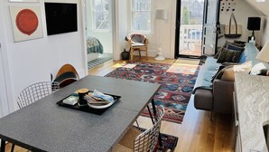 Una sala de estar moderna con comedor, un conjunto de sofás y vistas al exterior.