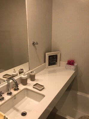 Un baño con un espejo grande, un lavabo y una zona de tocador.