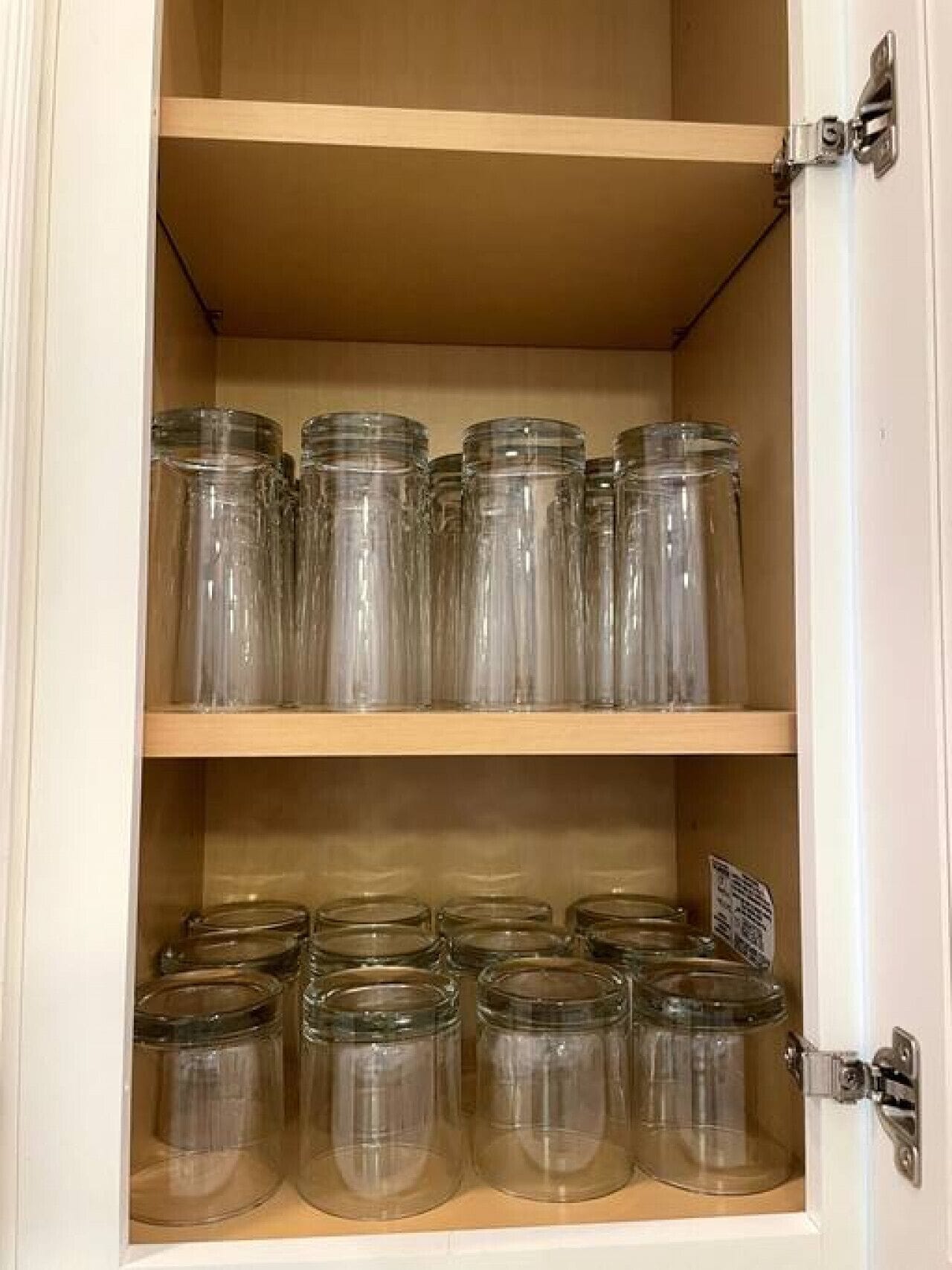 A cabinet with multiple shelves containing clear glass jars.