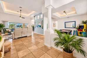 A spacious living area with a pool table, comfortable seating, and a view of the outdoors.