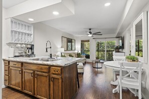 A modern kitchen with a large island, wooden cabinets, and a dining area with a white table and chairs.