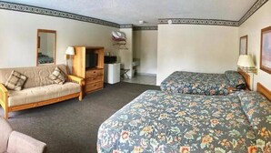 A hotel room with a sofa, two single beds, a dresser, a mirror, and a desk. - Dells Park Motel (Wisconsin Dells)