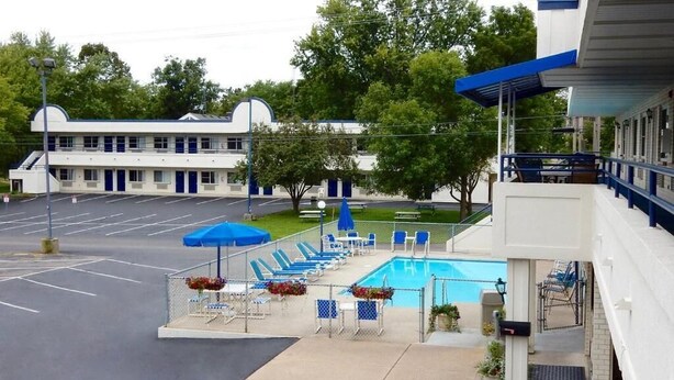 A motel with a swimming pool, outdoor seating, and a parking lot. - Dells Park Motel (Wisconsin Dells)