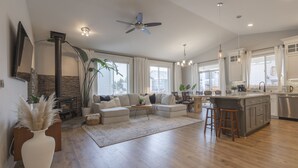A spacious living room with a fireplace, a sofa set, and a kitchen area with a bar. - Cozy new built home 10 minutes away from Portland (Vancouver)