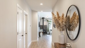 A hallway with a wooden floor, white walls, and a wooden console table with a mirror and decorative items. - Cozy new built home 10 minutes away from Portland (Vancouver)