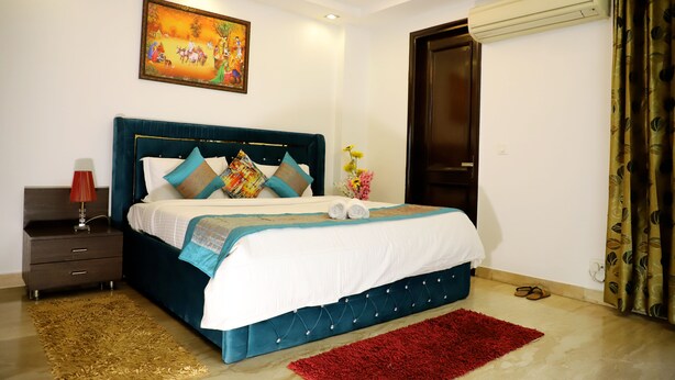 A neatly arranged bedroom with a bed, a nightstand, a red rug, and a painting on the wall.