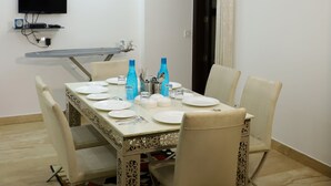 A dining area with a table set for four, a ceiling fan, a mounted television, and an air conditioning unit.