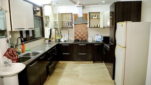 A modern kitchen with dark cabinetry, a white refrigerator, a sink, and a stove.