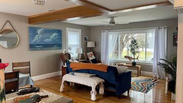 A spacious living room with a large window, a ceiling fan, and a view of the outdoors.