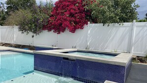 A rectangular swimming pool with blue mosaic tiles and a white fence in the background. - Private Pool & Hot Tub - Minutes from Disneyland - Comfort & Convenience (Anaheim)