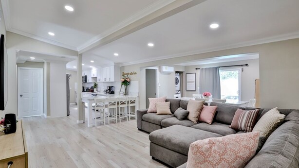 A spacious living area with a grey sectional sofa, a kitchen with white cabinets, and a dining area with a white table and chairs. - Private Pool & Hot Tub - Minutes from Disneyland - Comfort & Convenience (Anaheim)