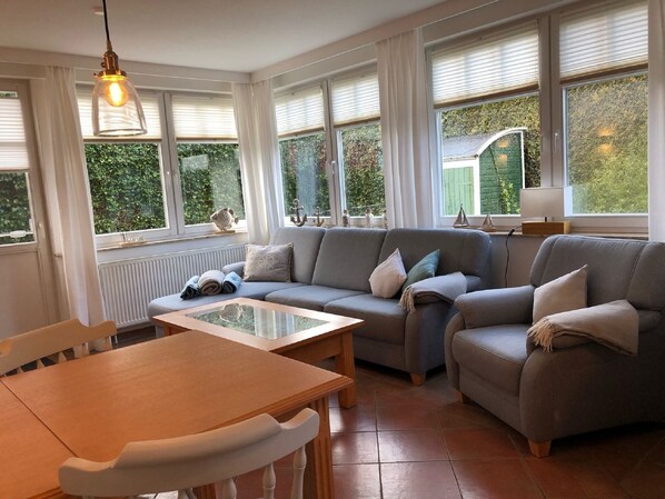 A cozy living room with a sofa, a wooden table, and a hanging light fixture.
