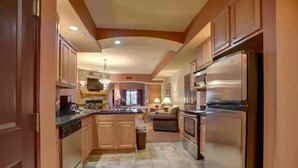Una cocina con armarios de madera, un refrigerador de acero inoxidable y piso de baldosas.