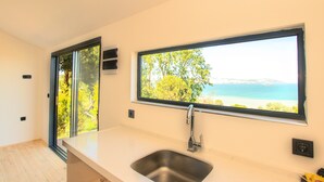 Una cocina moderna con un amplio ventanal que ofrece vistas a la playa y a los árboles.