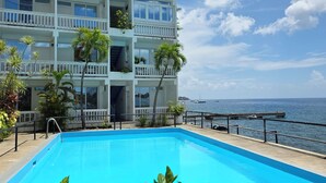 A two-story building with balconies, a swimming pool, and a view of the sea.