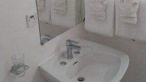 A bathroom with a white sink, a mirror, and two towels hanging on the wall.