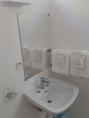 Een douche, handdoeken, zeep, toiletpapier