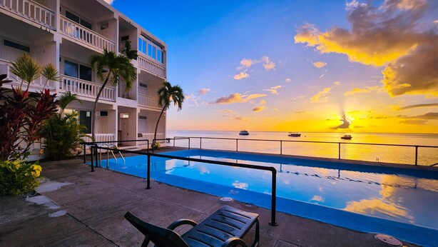A poolside area with a view of the ocean and a sunset.