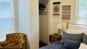 A bedroom with a bed, a chair, a nightstand, and a closet.