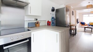 Ett modernt kök med en inbyggd ugn, en spishäll i rostfritt stål och ett stort kylskåp.