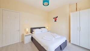 Ett välordnat hotellrum med en säng, sängbord, en garderob och en taklampa.
