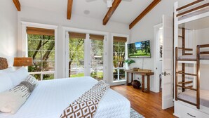 Un dormitorio con una cama grande, un ventilador de techo y vistas al exterior a través de amplios ventanales.