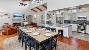 Una cocina amplia con una isla grande, electrodomésticos modernos y un comedor con una mesa y sillas de madera.