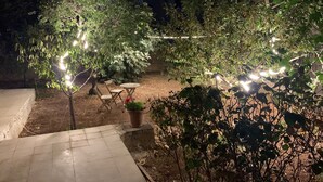 Un espace extérieur aménagé en patio, avec des guirlandes lumineuses, une petite table et des chaises.