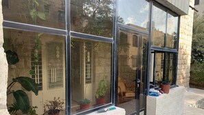 Un bâtiment moderne doté de grandes fenêtres en verre, de plantes en pot et d’un mur en pierre.