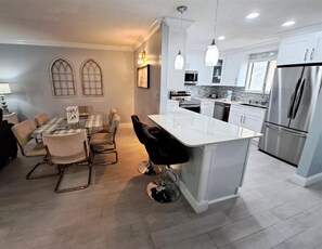 A modern kitchen with a central island, stainless steel appliances, and a dining area with a table and chairs.