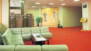 A lobby with a green sofa, a small table, and a red carpet. There is a large painting on the wall and a clock on the wall. - yuzawahotel (Yuzawa)