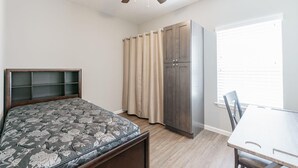 A bedroom with a bed, wardrobe, and a table. - Luxury Furnished Rental in Conway, AR Unit 206 (Conway)