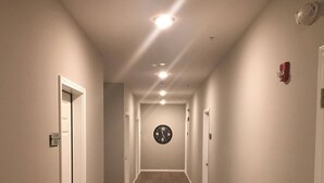 A hallway with wooden flooring, white walls, and doors on both sides. - Luxury Furnished Rental in Conway, AR Unit 206 (Conway)
