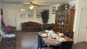 A dining area with a table set for four, surrounded by patterned sofas and a cabinet with glass doors. - Stylish Duplex with an Equine View (Indian Trail)