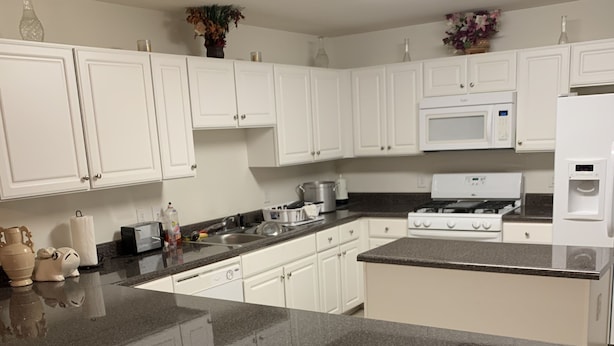 A modern kitchen with white cabinets, granite countertops, a stainless steel stove, and a built-in microwave. - Stylish Duplex with an Equine View (Indian Trail)