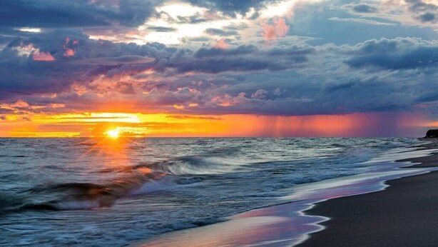 Una playa con olas y un atardecer.