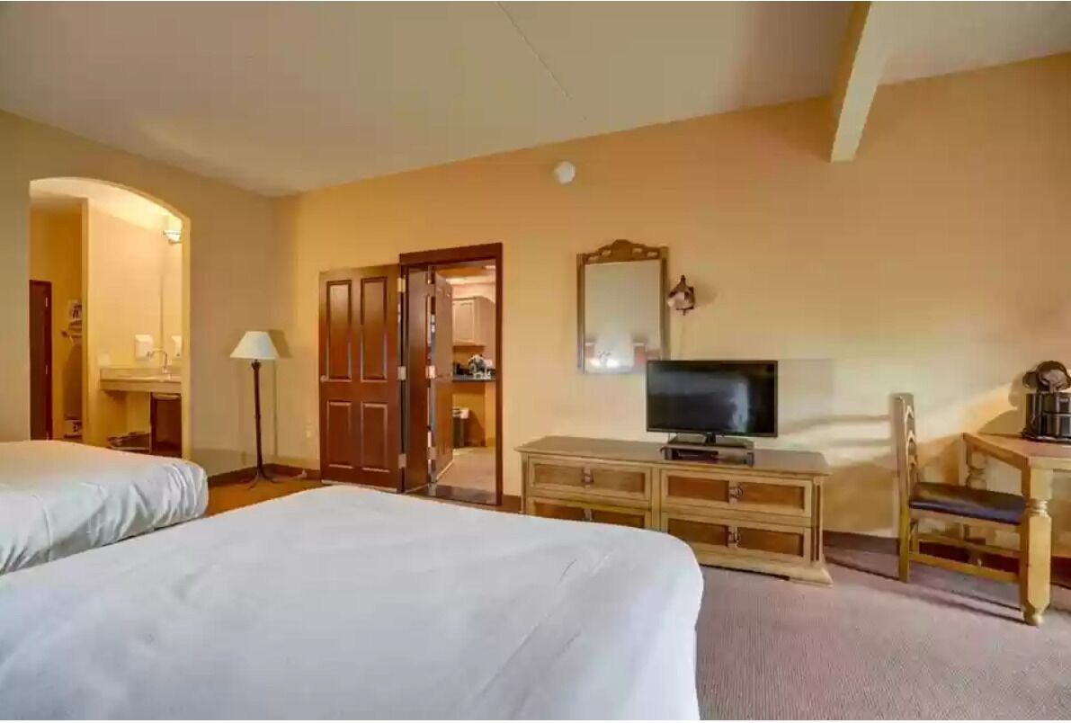 Een hotelkamer met twee bedden, een televisie, een bureau met stoel, een spiegel en een kledingkast.