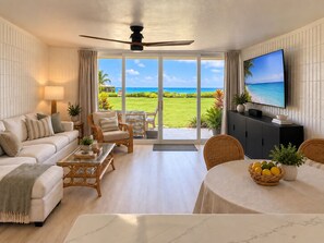A living room with a sofa, armchairs, a dining table, and a television. - Island Life Retreat-Ocean Front-Beach Access (Hauula)