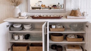 A white cabinet with shelves containing bowls, mugs, and baskets. - Island Life Retreat-Ocean Front-Beach Access (Hauula)